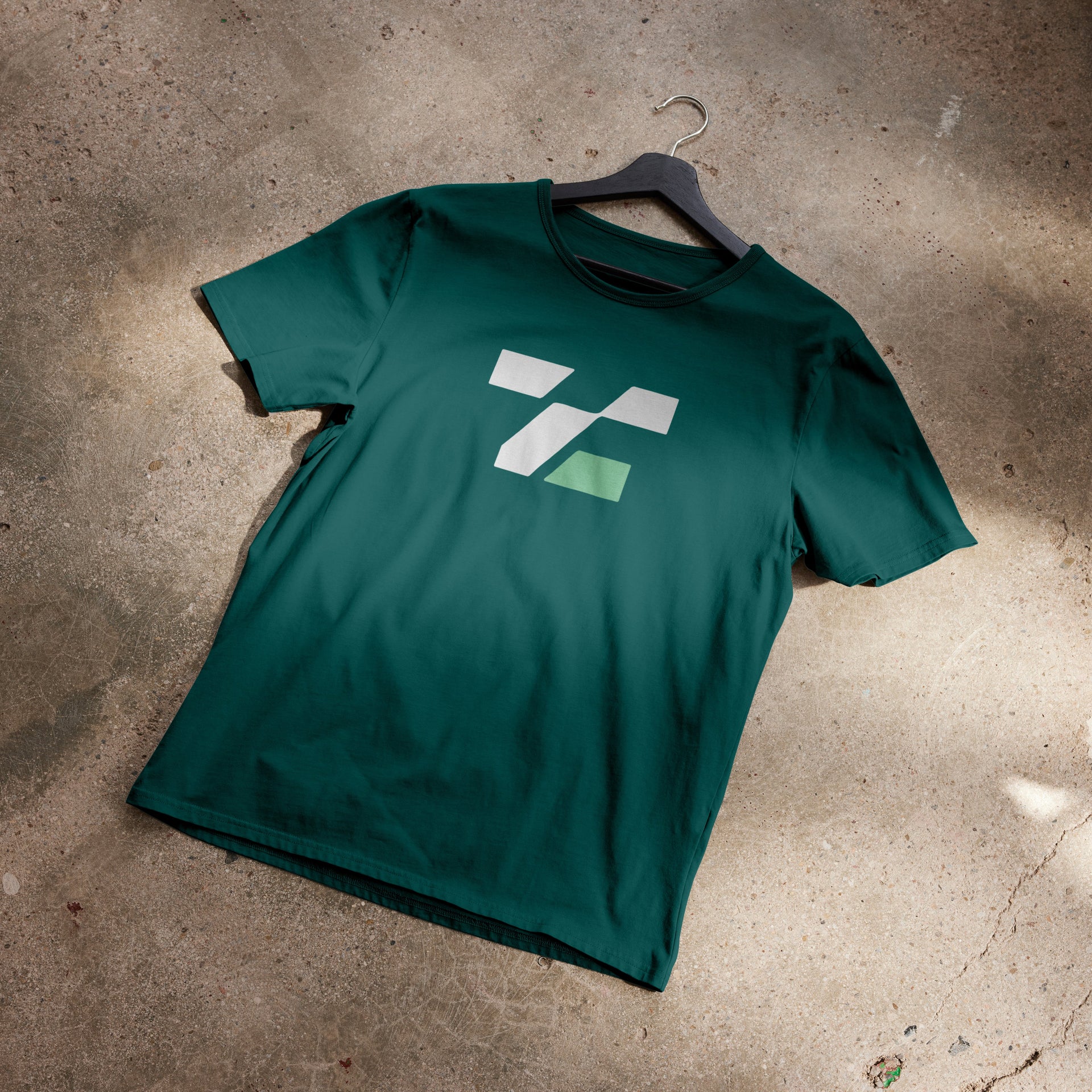 Green t-shirt with a logo on a concrete floor